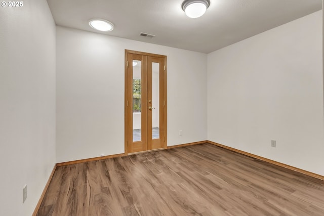 spare room featuring light hardwood / wood-style flooring and french doors