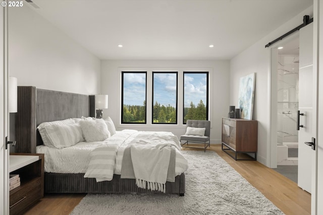 14410 Uplands Dr, Lake Oswego, OR 97034 - bedroom with a barn door, wood finished floors, recessed lighting, and connected bathroom
