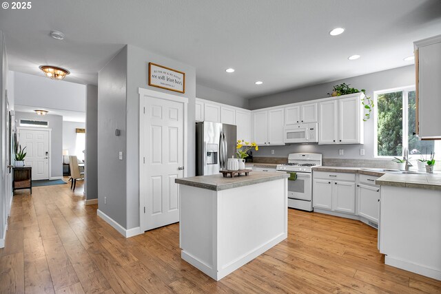 kitchen with a kitchen island, white appliances, light wood-style floors, recessed lighting, and white cabinetry