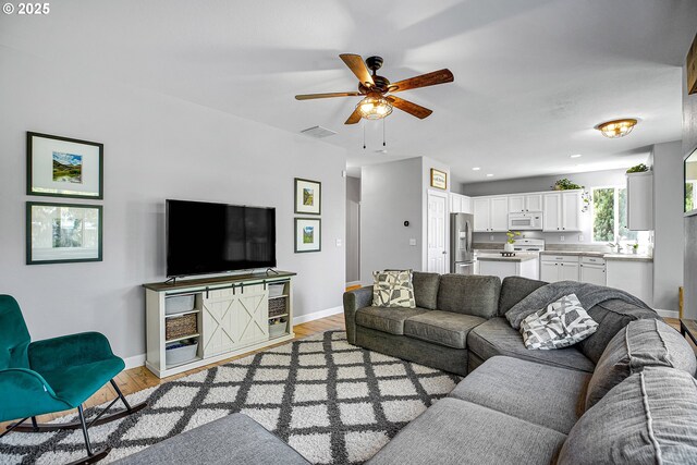 living room with a ceiling fan, visible vents, baseboards, light wood finished floors, and recessed lighting
