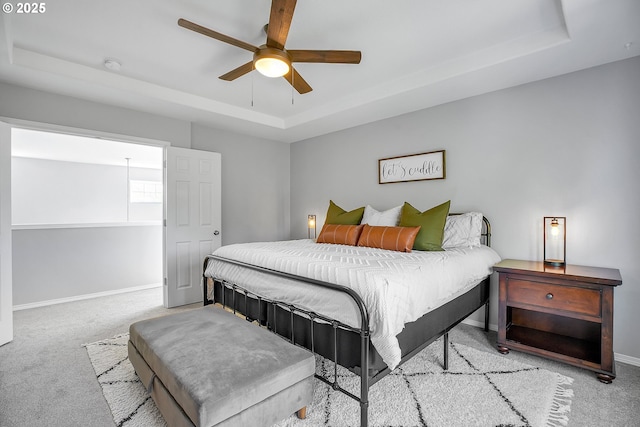 bedroom featuring baseboards, a raised ceiling, carpet, and ceiling fan