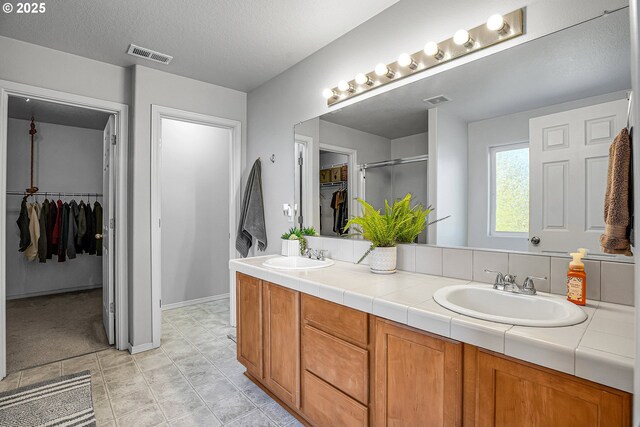 full bathroom with visible vents, a sink, a stall shower, and double vanity
