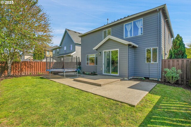 back of property with a patio, a fenced backyard, a trampoline, and a lawn
