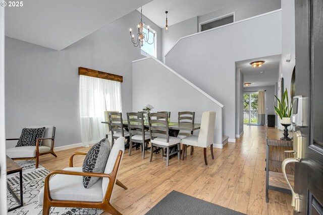 dining area featuring light wood-type flooring, baseboards, stairs, and a high ceiling