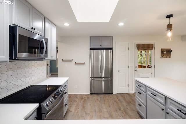 kitchen with stainless steel appliances, tasteful backsplash, light wood-style flooring, and light countertops