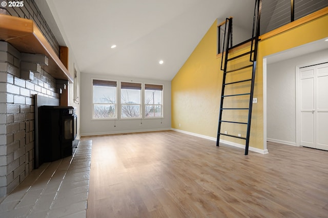 unfurnished living room featuring high vaulted ceiling, light wood-type flooring, and baseboards