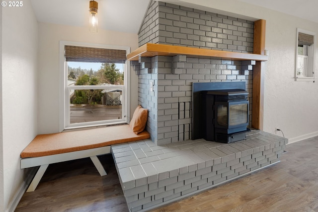 interior details with baseboards, wood finished floors, and a wood stove