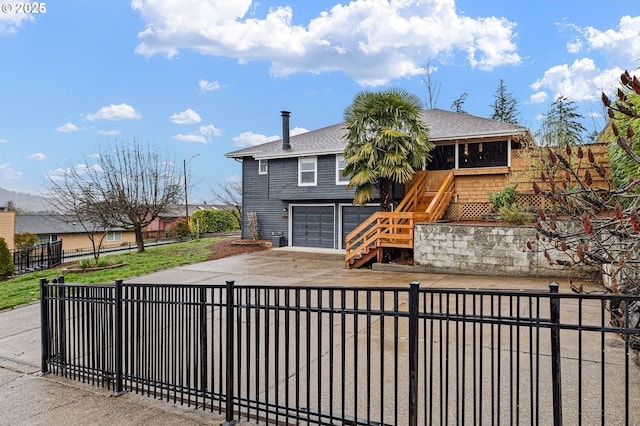 view of front facade with a shingled roof, stairs, concrete driveway, a garage, and a fenced front yard