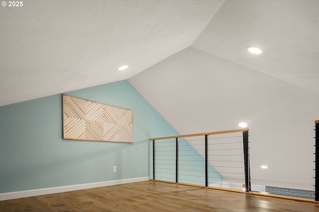 additional living space with visible vents, baseboards, wood finished floors, and vaulted ceiling