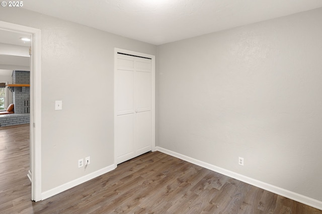 unfurnished bedroom with a closet, baseboards, wood finished floors, and a fireplace