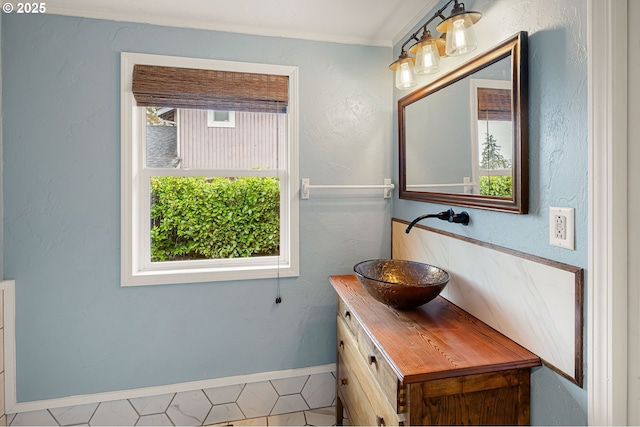 bathroom with baseboards, plenty of natural light, vanity, and a textured wall