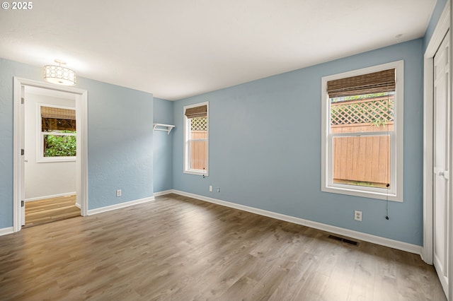 empty room with wood finished floors, visible vents, and baseboards