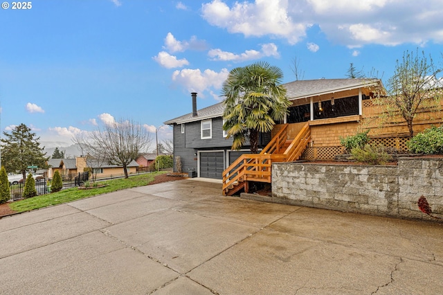 exterior space featuring driveway, fence, stairway, a shingled roof, and a garage