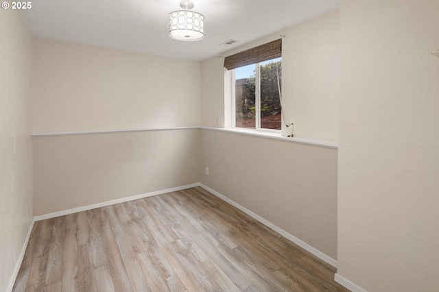 empty room featuring wood finished floors, visible vents, and baseboards