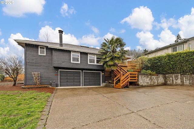 exterior space featuring driveway, an attached garage, and stairs