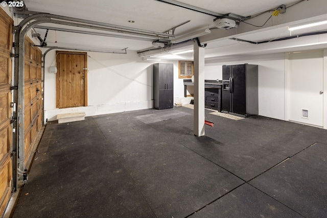 garage featuring a garage door opener and black fridge