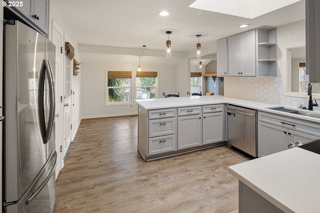 kitchen featuring open shelves, a peninsula, a sink, decorative backsplash, and stainless steel appliances