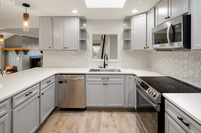 kitchen featuring open shelves, a sink, stainless steel appliances, light wood-type flooring, and backsplash