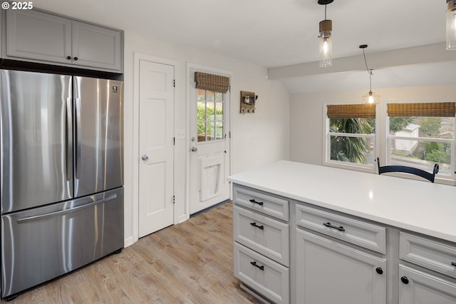 kitchen with light wood finished floors, pendant lighting, light countertops, lofted ceiling, and freestanding refrigerator