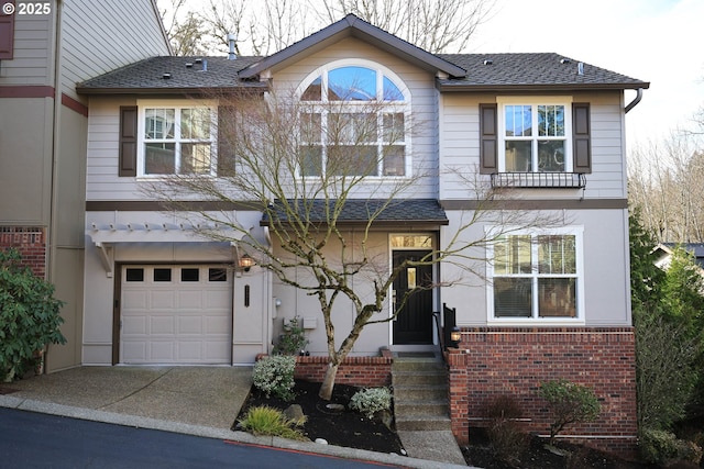 view of front of property with an attached garage, roof with shingles, concrete driveway, and brick siding