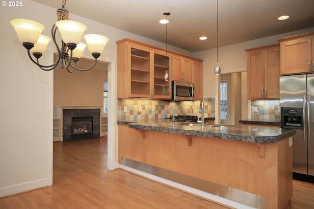 kitchen with glass insert cabinets, light wood-type flooring, and appliances with stainless steel finishes