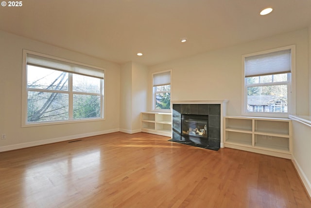 unfurnished living room featuring recessed lighting, a fireplace, baseboards, and wood finished floors