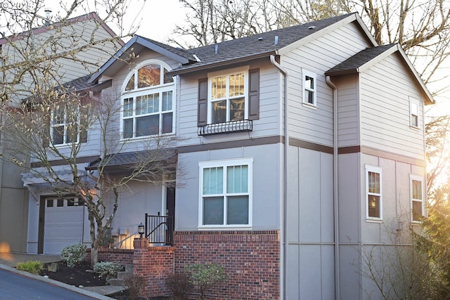 view of front of home featuring a garage, brick siding, and a shingled roof