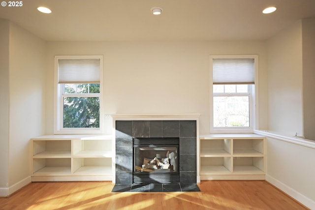 unfurnished living room featuring recessed lighting, baseboards, wood finished floors, and a tile fireplace