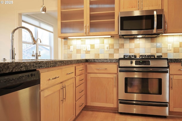 kitchen with tasteful backsplash, light wood-style flooring, glass insert cabinets, stainless steel appliances, and light brown cabinetry