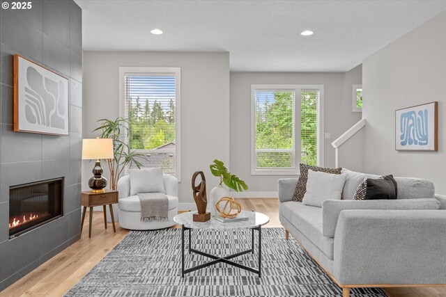 9014 SW Steens Ln, Portland, OR 97225 - living area with wood finished floors, healthy amount of natural light, a tiled fireplace, recessed lighting, and baseboards