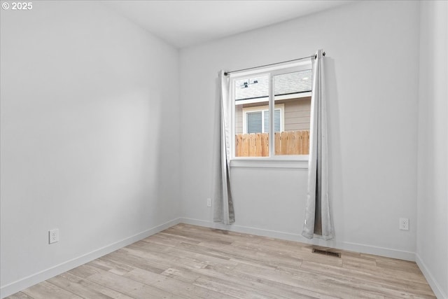 empty room featuring visible vents, baseboards, and wood finished floors