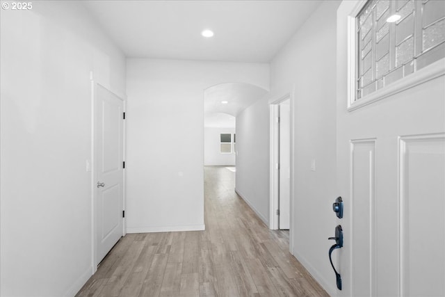 hall with recessed lighting, light wood-type flooring, arched walkways, and baseboards