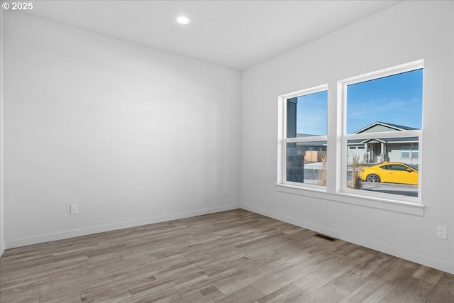 empty room featuring recessed lighting, wood finished floors, visible vents, and baseboards