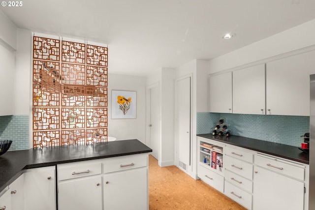 6945 SW 7th Ave, Portland, OR 97219 - kitchen featuring dark countertops, tasteful backsplash, and white cabinetry