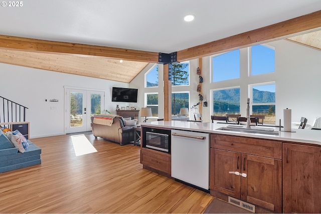 kitchen with open floor plan, white dishwasher, beam ceiling, black microwave, and a sink