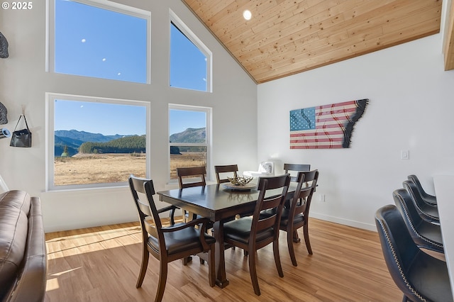 dining space featuring high vaulted ceiling, wooden ceiling, a mountain view, wood finished floors, and baseboards