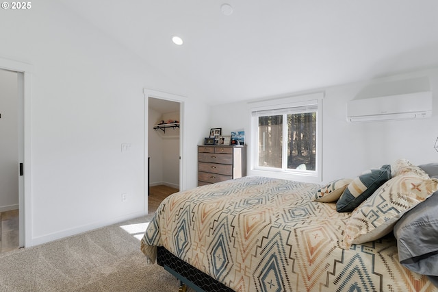 bedroom with baseboards, lofted ceiling, carpet, a spacious closet, and a wall mounted AC