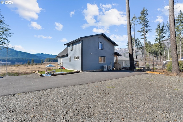 view of property exterior with driveway, fence, and a mountain view