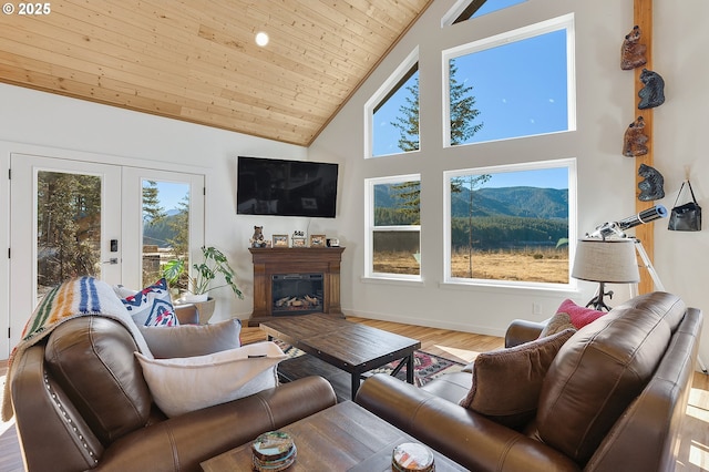 living area featuring french doors, a glass covered fireplace, wood ceiling, wood finished floors, and high vaulted ceiling