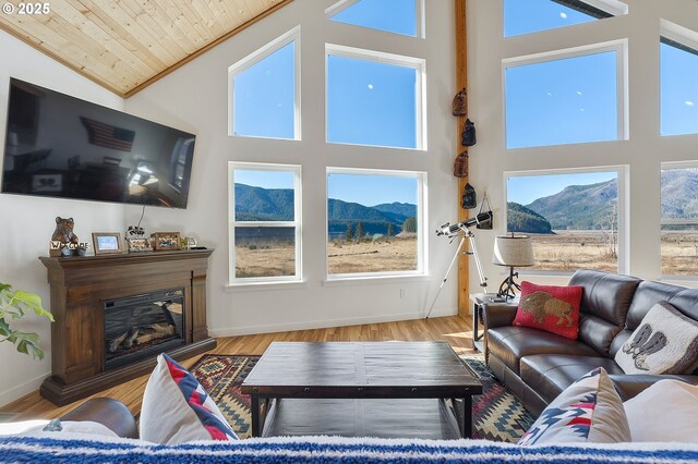 living room featuring wood finished floors, wooden ceiling, a glass covered fireplace, and a mountain view