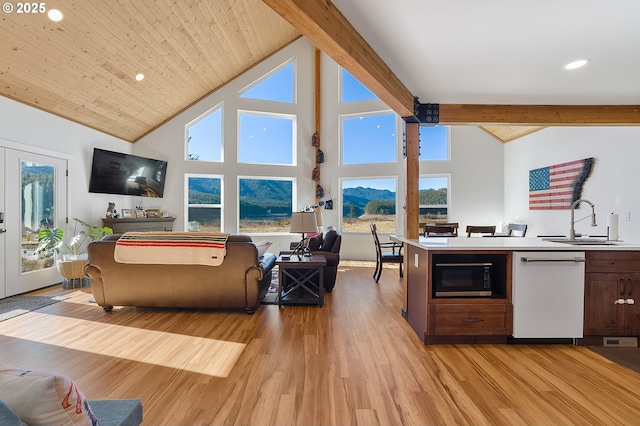 kitchen featuring light wood finished floors, open floor plan, a sink, black microwave, and dishwasher