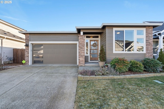 view of front of home with a garage, fence, driveway, stone siding, and a front lawn