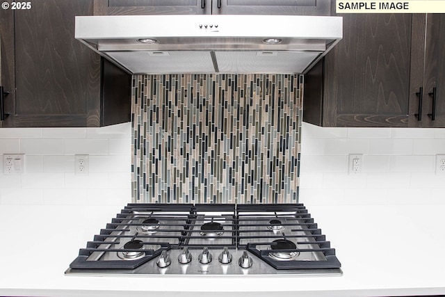 interior details with tasteful backsplash, dark brown cabinetry, stainless steel gas cooktop, and exhaust hood