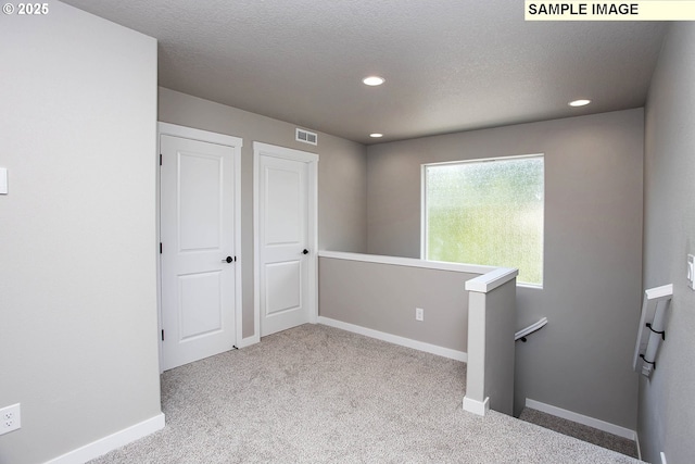 carpeted empty room featuring a textured ceiling