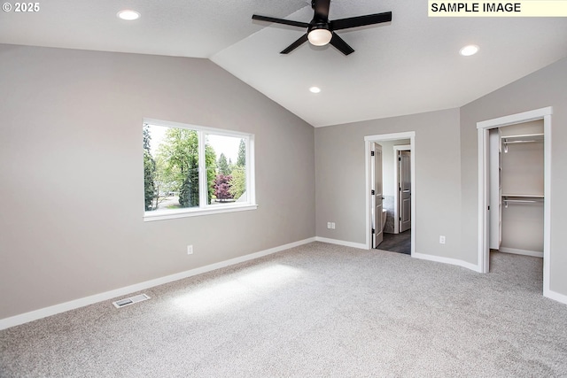 unfurnished bedroom featuring vaulted ceiling, a walk in closet, carpet, and a closet