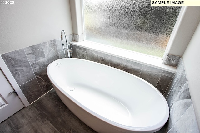 bathroom with wood-type flooring, a bathtub, and tile walls