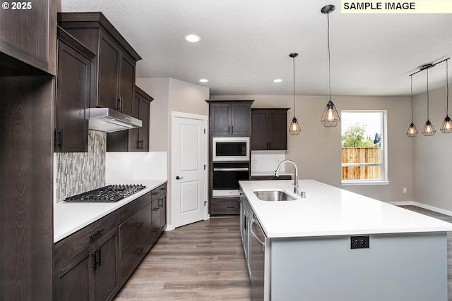 kitchen with pendant lighting, sink, a center island with sink, and appliances with stainless steel finishes