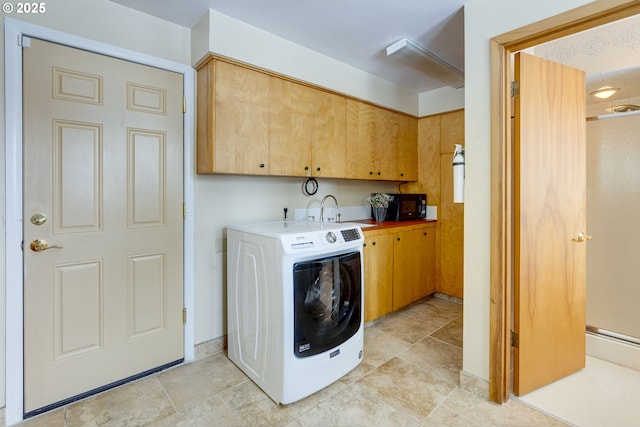 clothes washing area featuring sink, washer / dryer, and cabinets