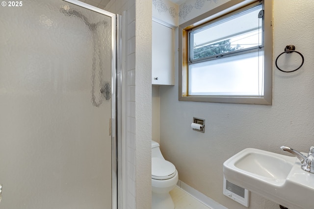 bathroom with toilet, a shower with door, and sink