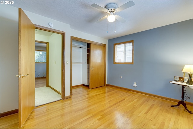 bedroom with ceiling fan, light hardwood / wood-style flooring, a closet, and a textured ceiling